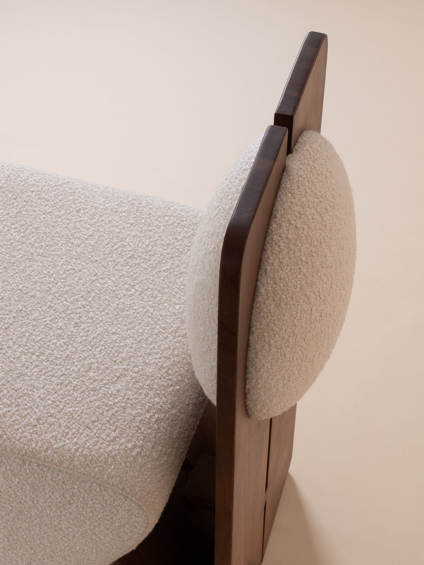 Close-up of cream bouclé upholstery and walnut wood backrest on Moment 2.5 W Chair