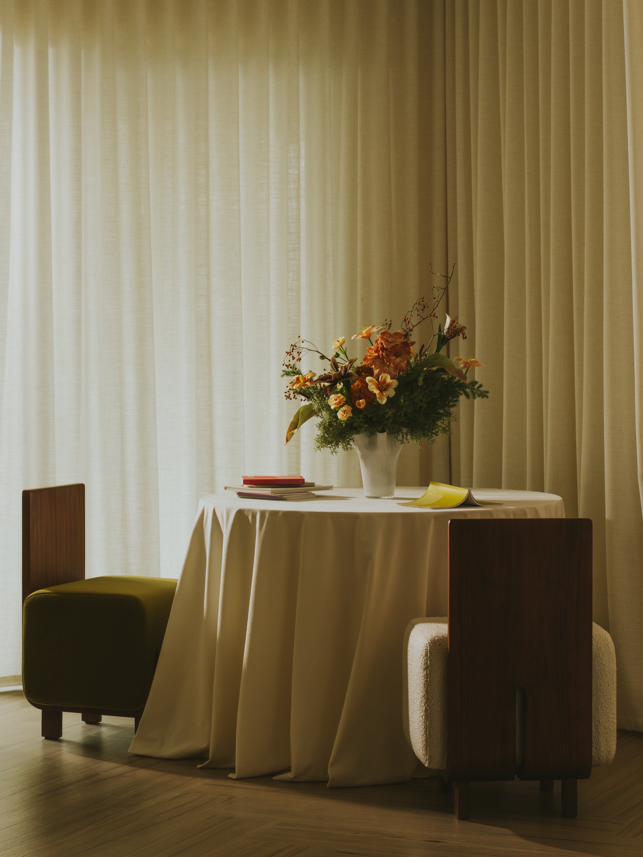 Form + Moment Onigi Chairs at modern dining table: one in cream white bouclé, one in luxurious olive green velvet with walnut wood frames