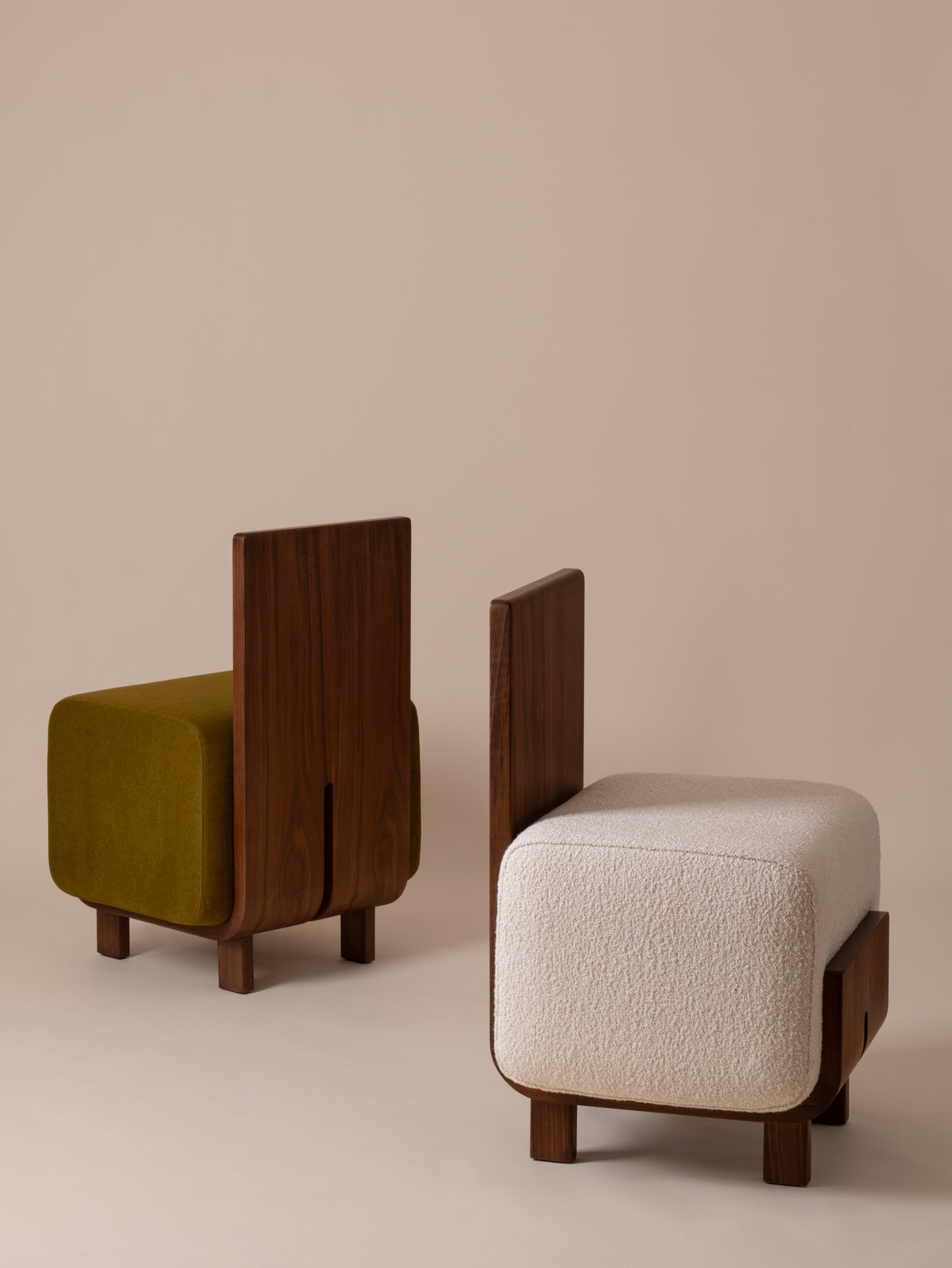Moment 2.5 Onigi Chairs against warm neutral studio background: one in cream bouclé, one in olive green velvet with walnut wood frames