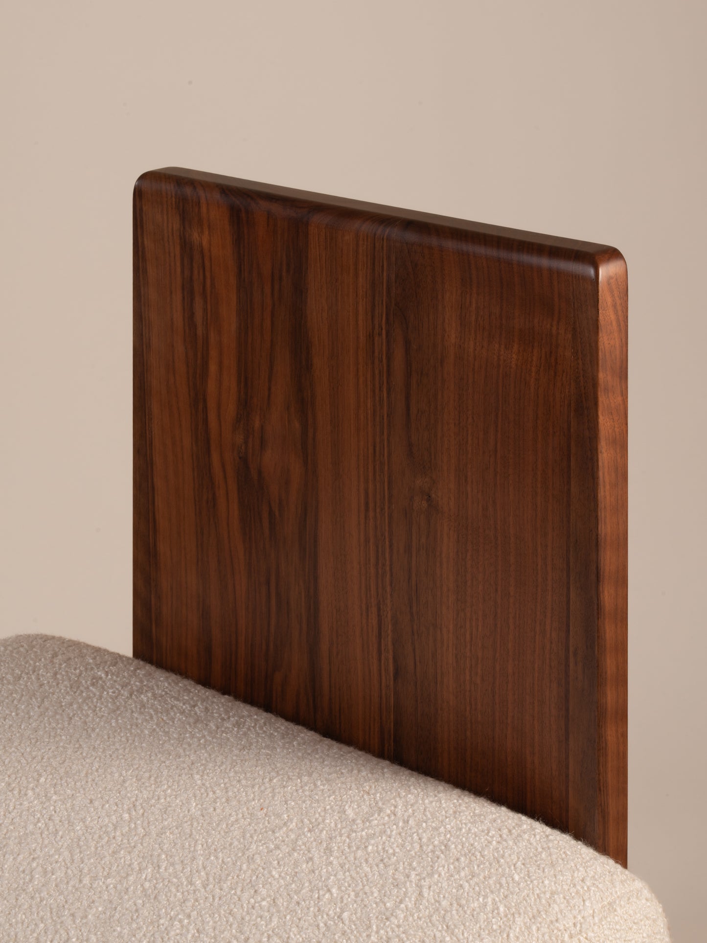 Close-up detail of walnut wood grain backrest on Moment 2.5 Onigi Chair with plush upholstery