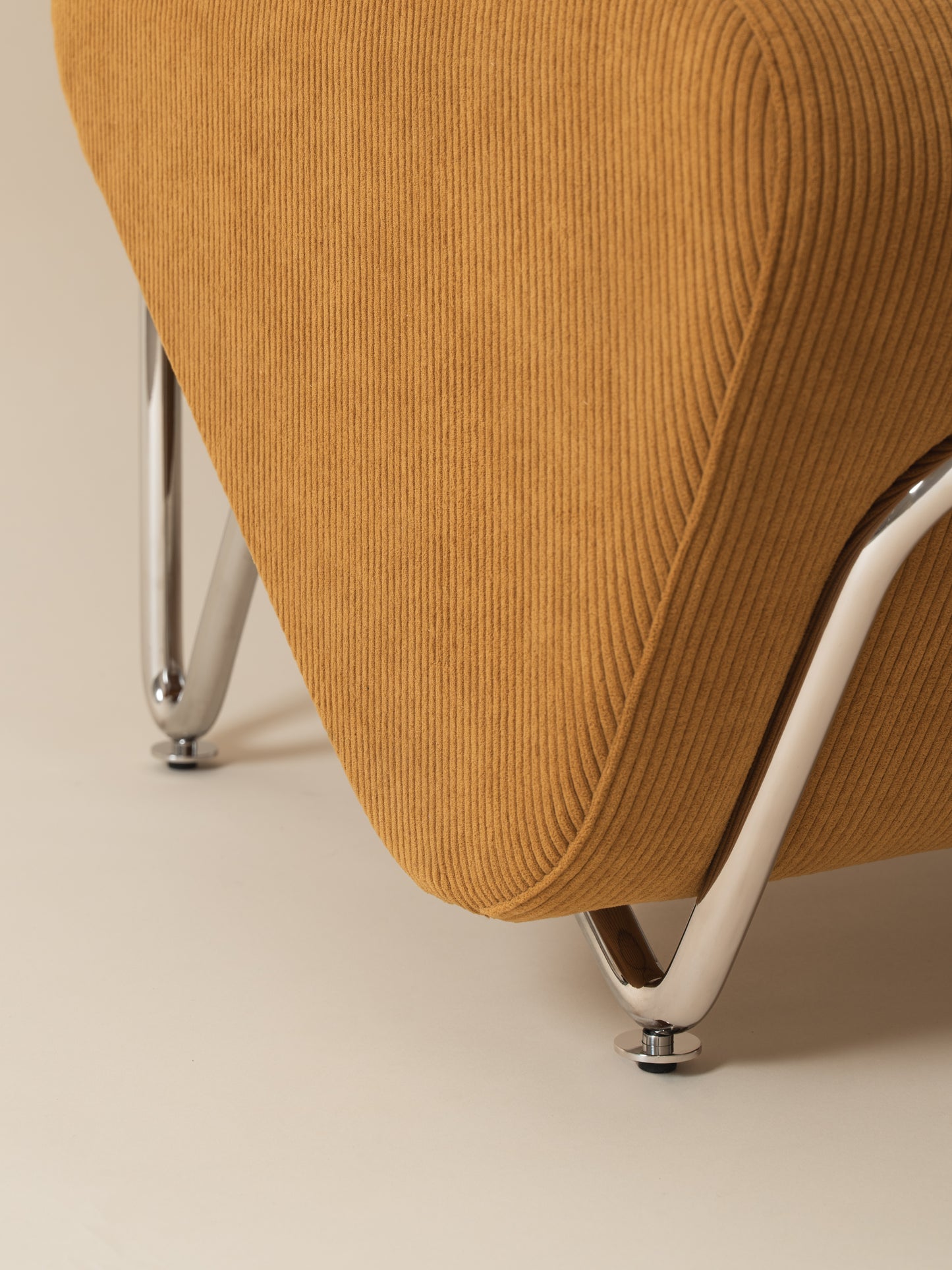 Close-up detail of chrome-plated stainless steel frame, legs and warm mustard corduroy upholstery on Moment 2.5 Trolley Lounge Chair