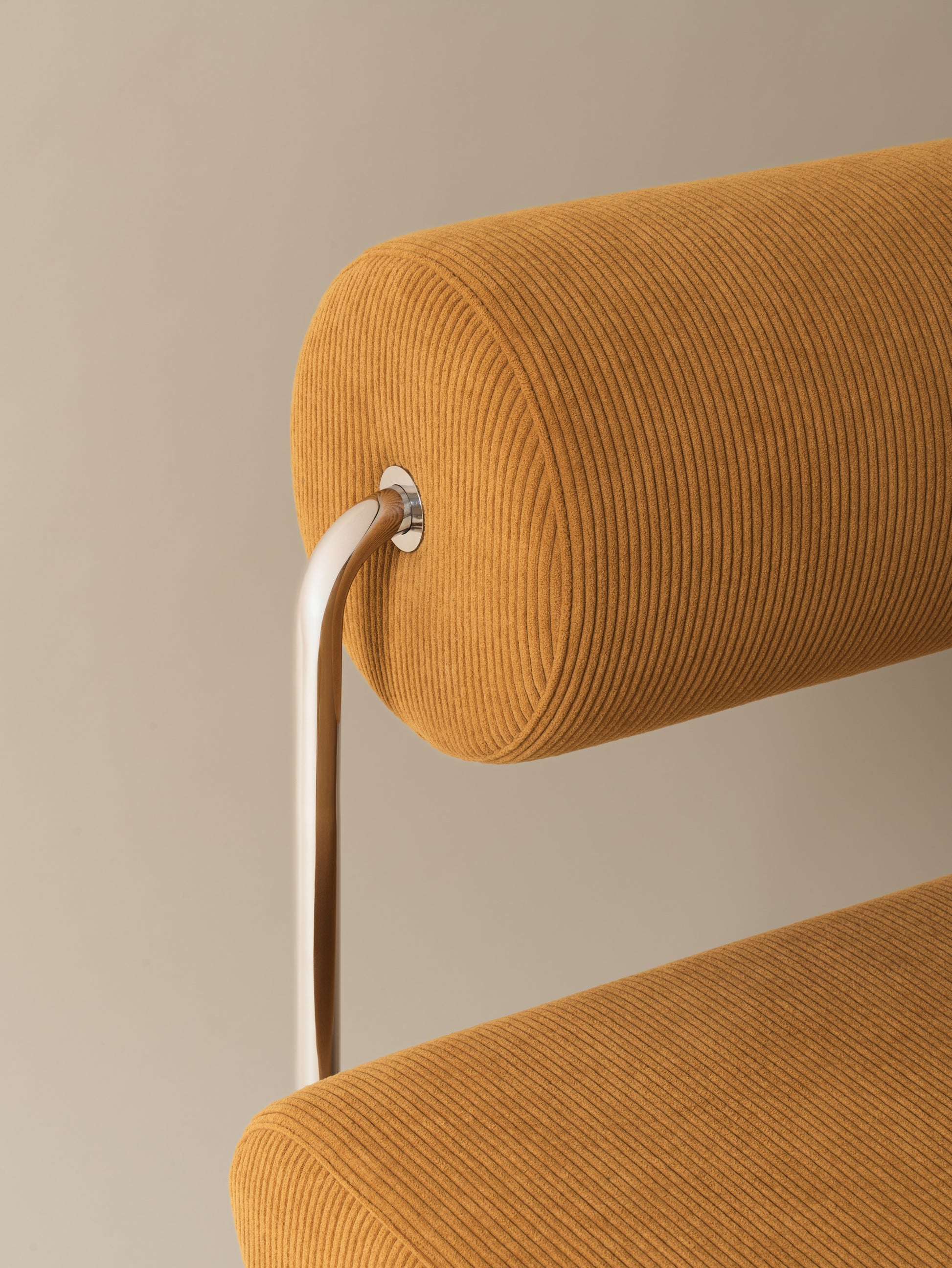 Close-up of chrome-plated stainless steel frame, backrest structure and plush warm mustard corduroy cushion on Moment 2.5 Trolley Lounge Chair