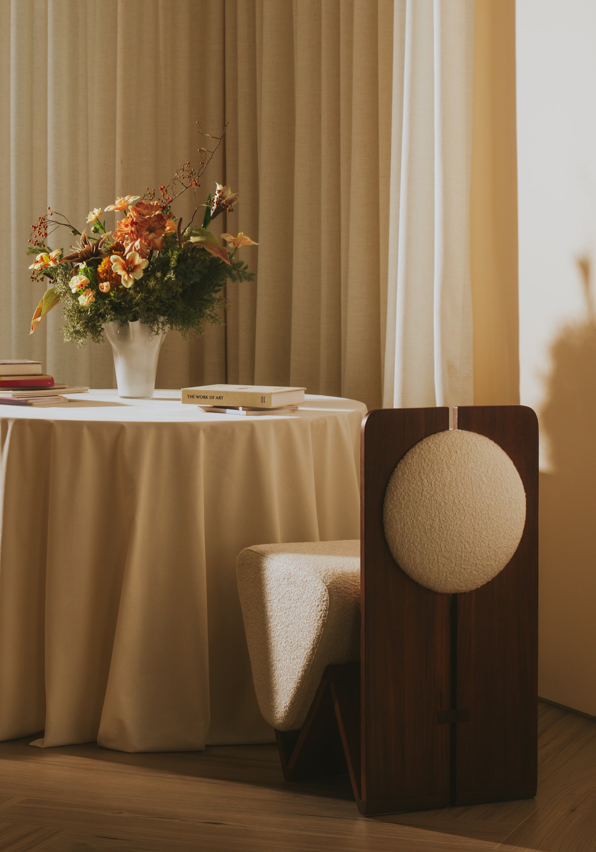 Moment 2.5 W Chair at modern dining table, showing signature W-shaped walnut frame and cream bouclé seat
