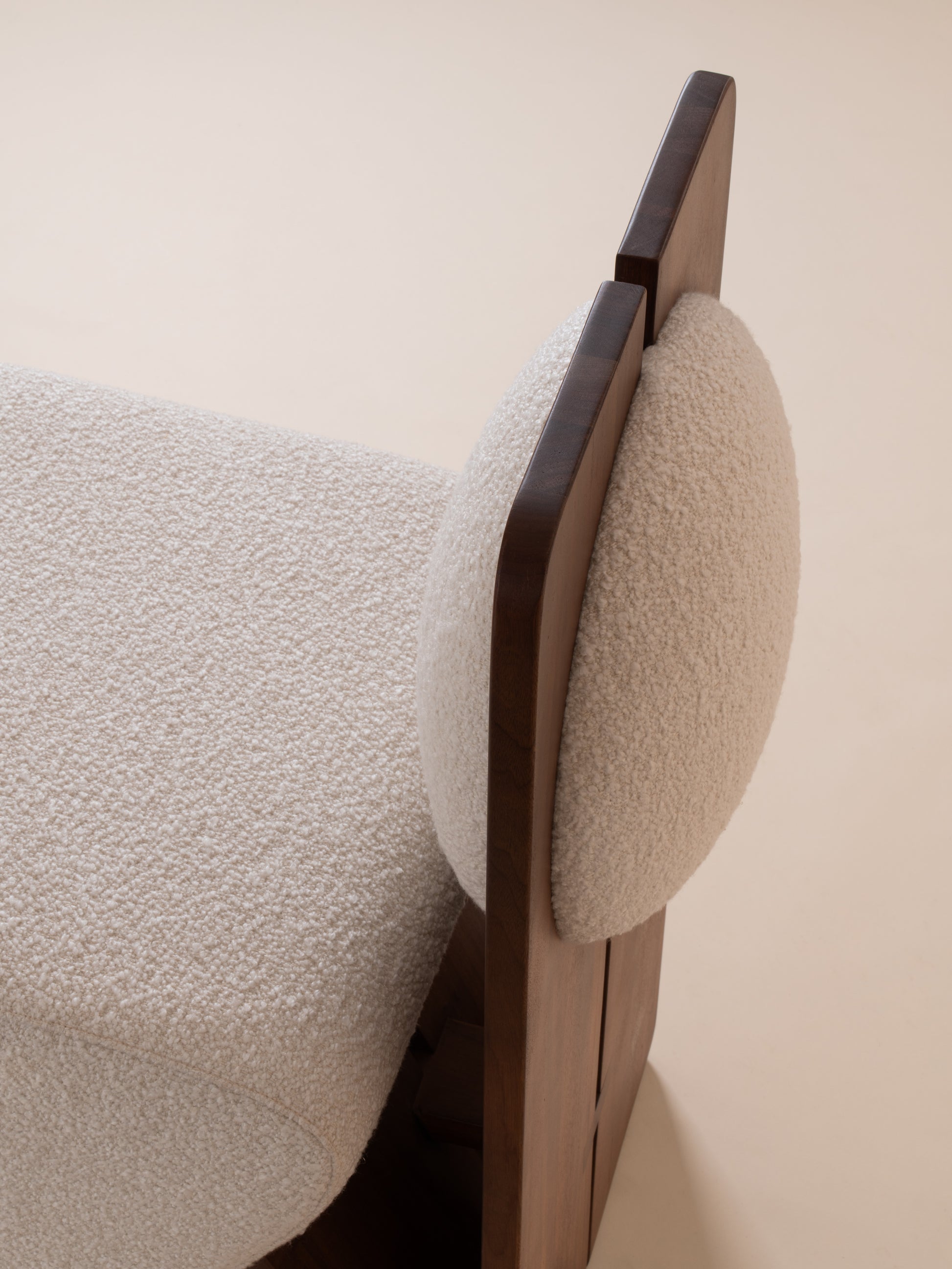 Close-up of cream bouclé upholstery and walnut wood backrest on Moment 2.5 W Chair
